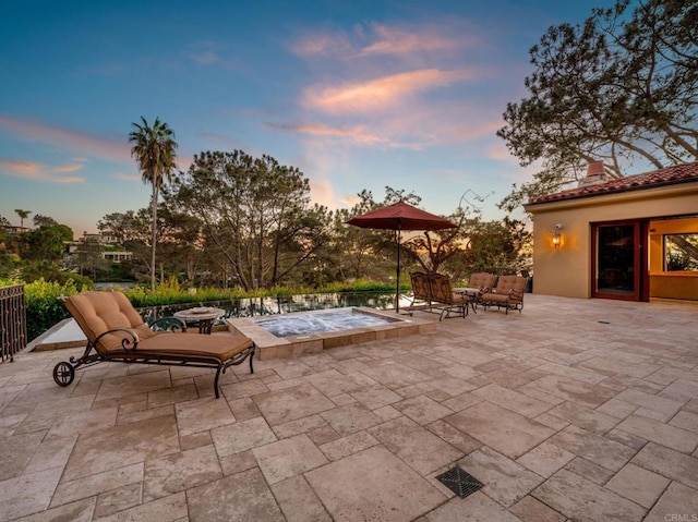 patio terrace at dusk featuring a swimming pool