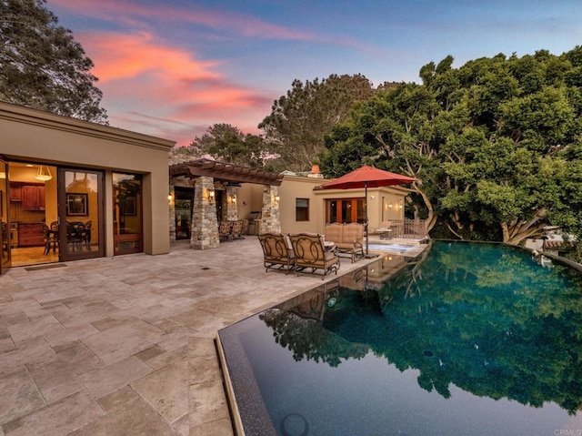 pool at dusk featuring a patio area and an outdoor hangout area