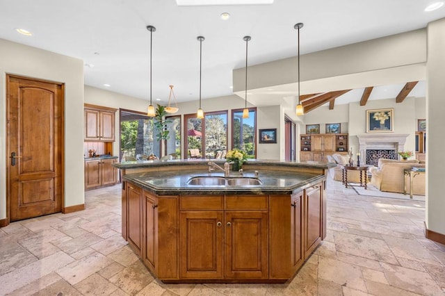 kitchen featuring lofted ceiling with beams, sink, pendant lighting, and a kitchen island with sink