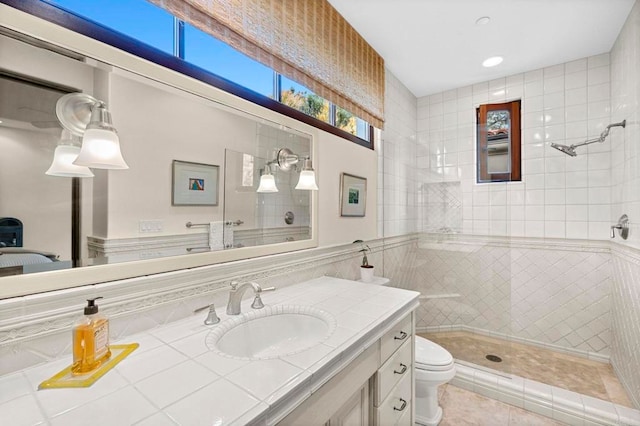 bathroom featuring tiled shower, tile patterned floors, toilet, vanity, and tile walls