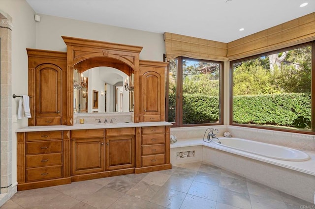 bathroom with vanity, a relaxing tiled tub, and plenty of natural light