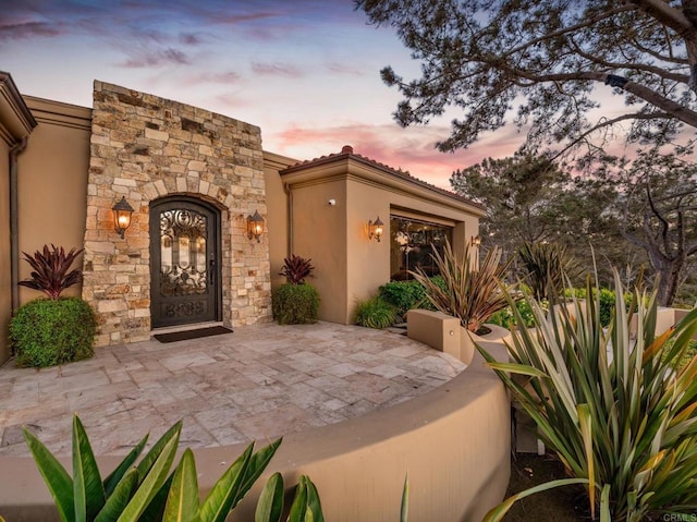 exterior entry at dusk with a patio