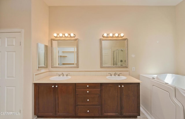 bathroom with vanity with extensive cabinet space, dual sinks, and a bathtub