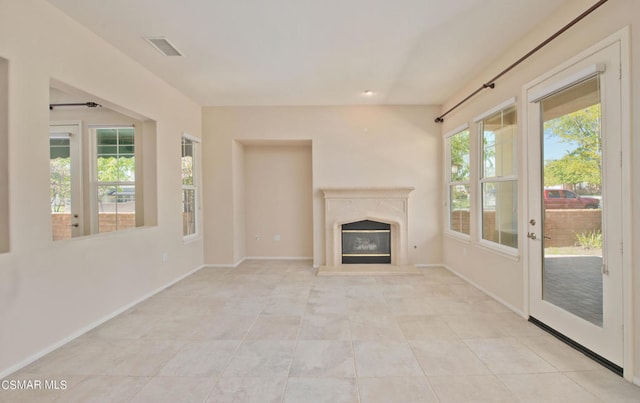 unfurnished living room featuring a premium fireplace and light tile floors