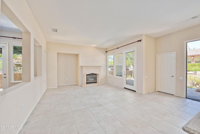 unfurnished living room featuring a premium fireplace, a healthy amount of sunlight, and light tile floors