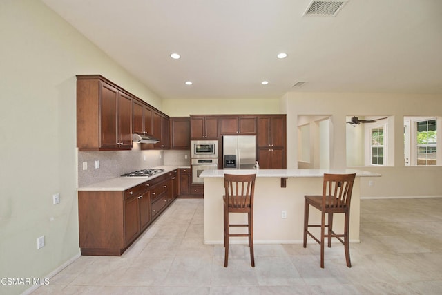 kitchen featuring appliances with stainless steel finishes, a kitchen breakfast bar, a kitchen island, and light tile floors