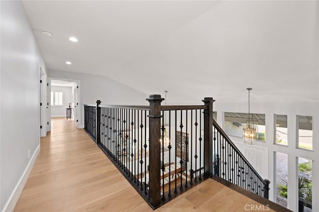 hallway featuring light wood-type flooring, plenty of natural light, and a notable chandelier