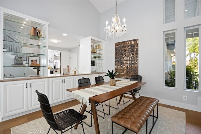 dining room featuring light wood-type flooring, high vaulted ceiling, and a notable chandelier