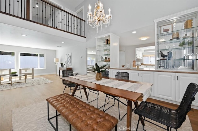 dining space featuring a towering ceiling, light hardwood / wood-style floors, and a notable chandelier