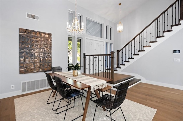 dining room featuring an inviting chandelier, high vaulted ceiling, and light wood-type flooring