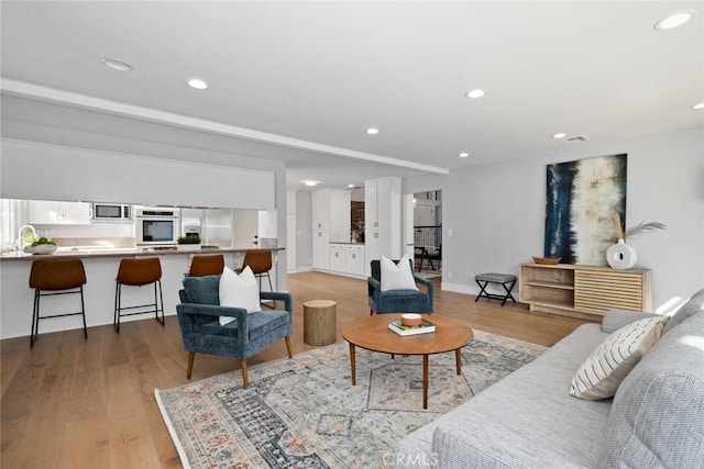 living room with light hardwood / wood-style flooring and sink