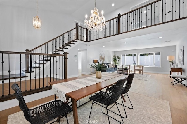 dining space with light wood-type flooring, high vaulted ceiling, and an inviting chandelier