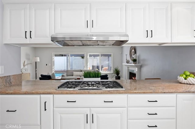 kitchen featuring kitchen peninsula, white cabinetry, extractor fan, and stainless steel gas stovetop