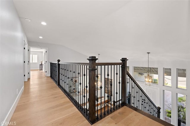 corridor with a chandelier, light wood-type flooring, and a wealth of natural light