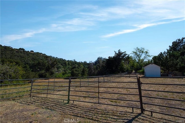 view of gate with a rural view and an outbuilding