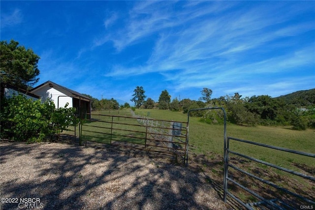 view of gate with a yard and a rural view