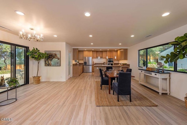 dining area featuring a healthy amount of sunlight, light hardwood / wood-style floors, and a notable chandelier