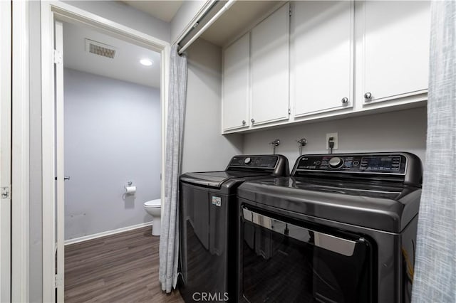 laundry room featuring cabinets, dark hardwood / wood-style floors, and washer and dryer