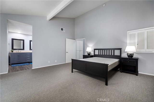 bedroom with ensuite bathroom, beamed ceiling, carpet floors, and high vaulted ceiling