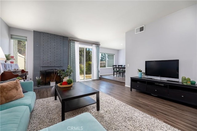 living room featuring plenty of natural light, dark hardwood / wood-style floors, and a brick fireplace