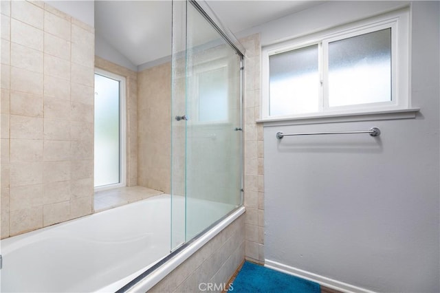 bathroom with combined bath / shower with glass door and vaulted ceiling