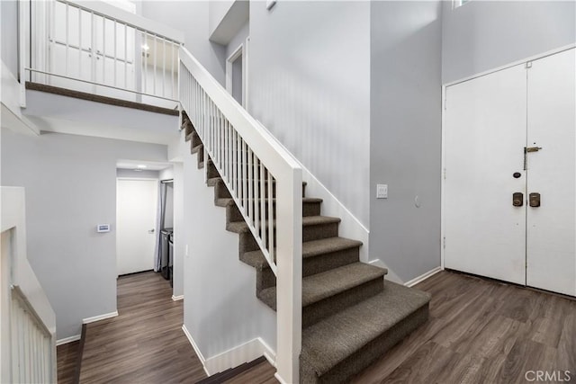 stairway featuring a towering ceiling and hardwood / wood-style flooring