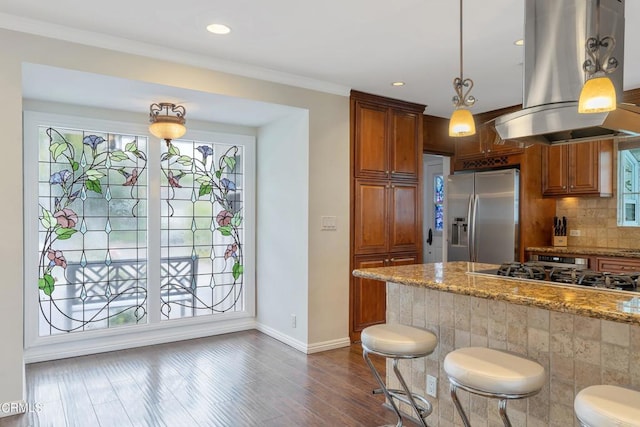 kitchen featuring decorative light fixtures, island exhaust hood, light stone countertops, dark wood-type flooring, and appliances with stainless steel finishes