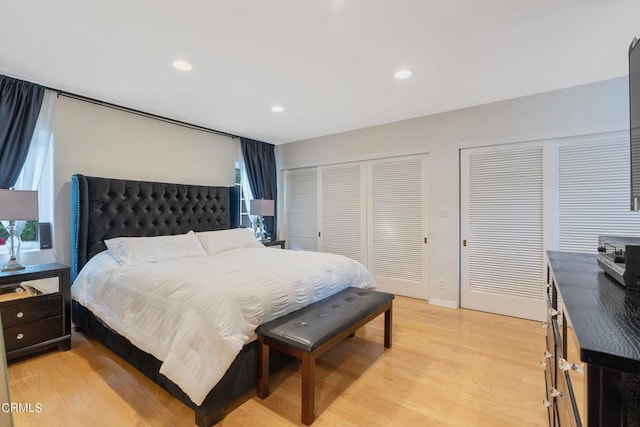 bedroom featuring light wood-type flooring and multiple closets