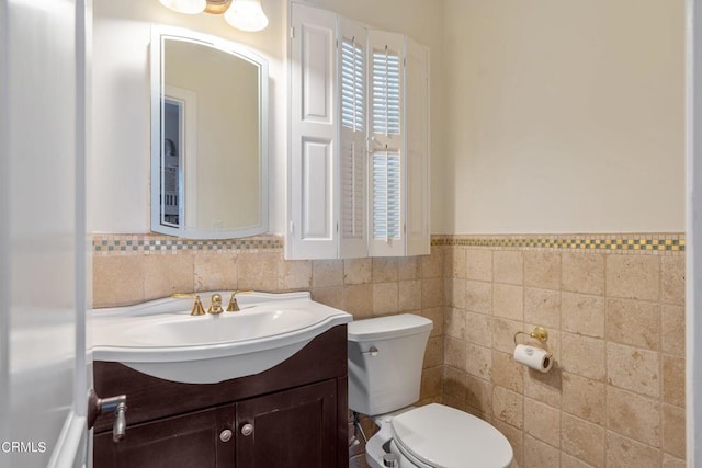 bathroom featuring tile walls, toilet, and vanity