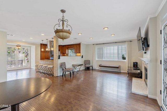 interior space with a healthy amount of sunlight, ornamental molding, and dark hardwood / wood-style flooring