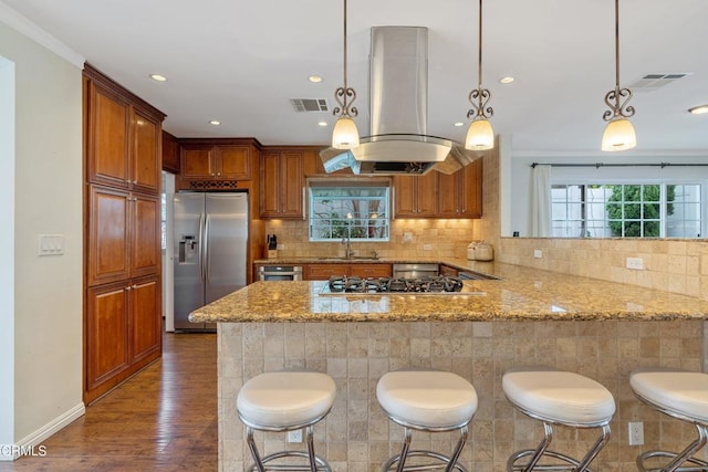 kitchen featuring kitchen peninsula, island exhaust hood, hanging light fixtures, dark wood-type flooring, and appliances with stainless steel finishes