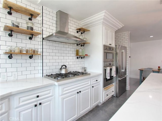 kitchen featuring backsplash, light stone counters, white cabinets, and wall chimney range hood