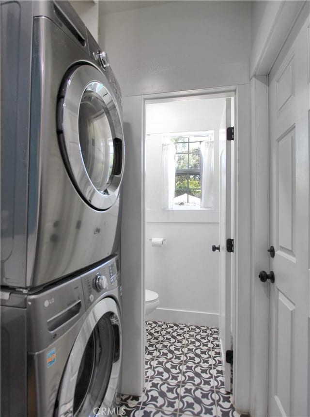 laundry room with light tile patterned flooring and stacked washer / drying machine