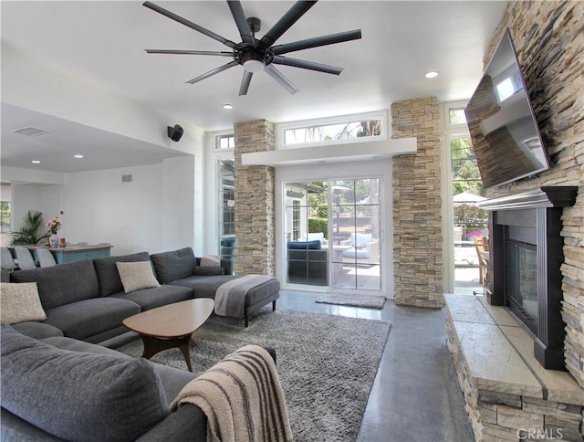 living room with ceiling fan, concrete flooring, and a fireplace