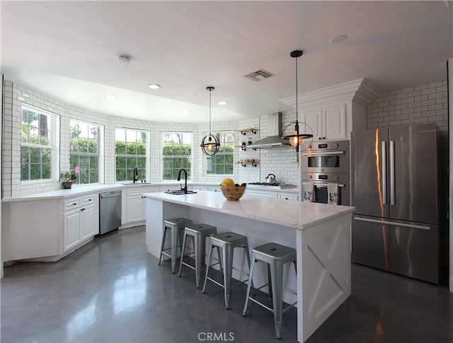 kitchen with white cabinetry, a center island with sink, wall chimney exhaust hood, and stainless steel appliances