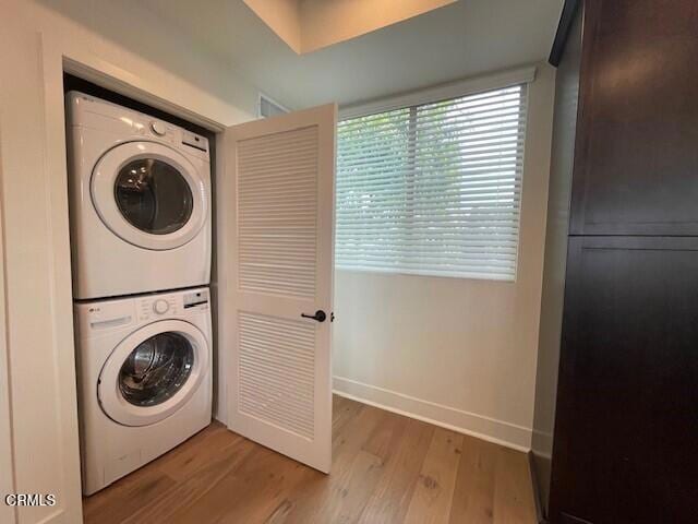 laundry area with hardwood / wood-style flooring and stacked washing maching and dryer