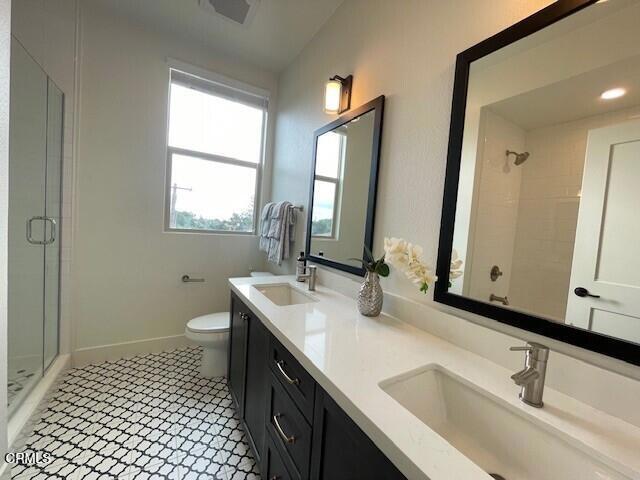 bathroom featuring tile patterned flooring, vanity, toilet, and a shower with shower door