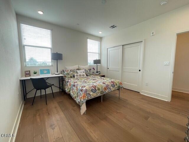 bedroom featuring a closet, light hardwood / wood-style floors, and multiple windows