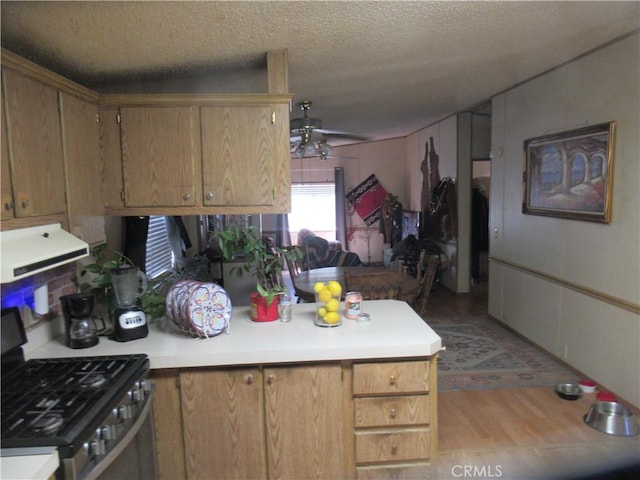 kitchen featuring ceiling fan, extractor fan, gas stove, kitchen peninsula, and a textured ceiling