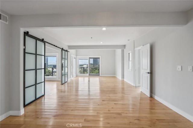 spare room with a barn door and light wood-type flooring