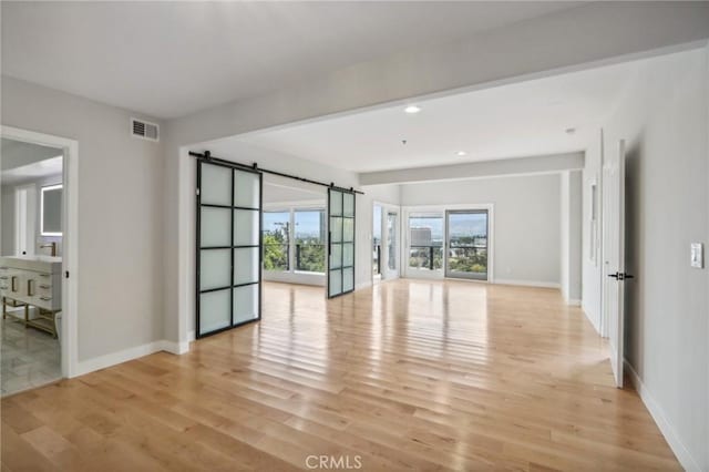 spare room featuring light hardwood / wood-style floors and a barn door