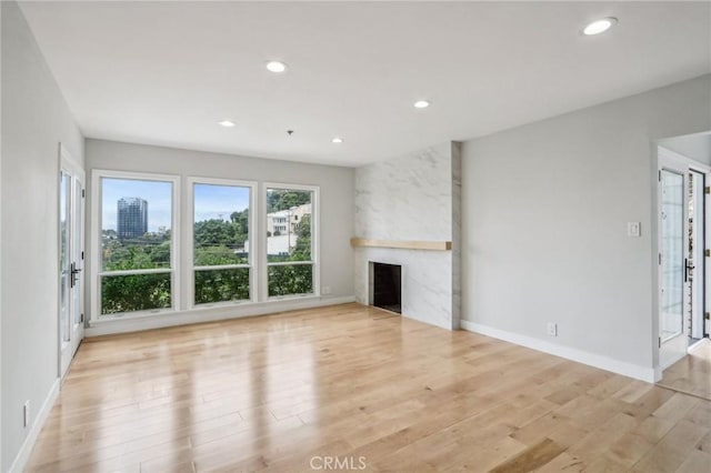 unfurnished living room featuring a premium fireplace and light hardwood / wood-style flooring