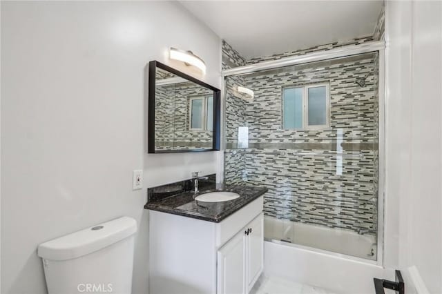 full bathroom with bath / shower combo with glass door, toilet, and vanity