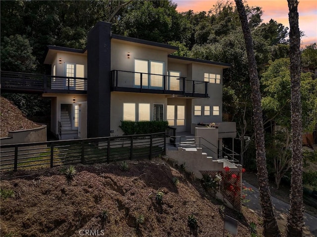 back house at dusk featuring a balcony