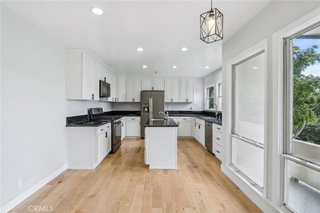 kitchen featuring white cabinetry, a center island with sink, stainless steel appliances, hanging light fixtures, and sink