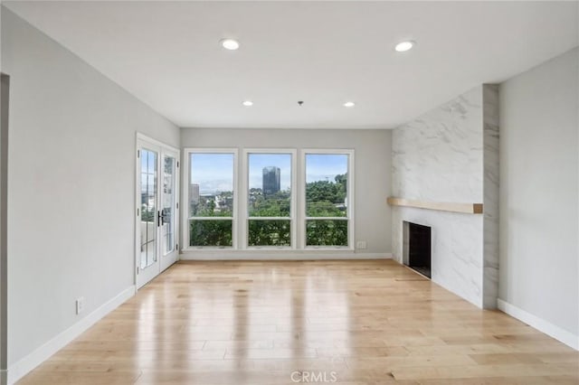 unfurnished living room with light hardwood / wood-style flooring, french doors, and a fireplace