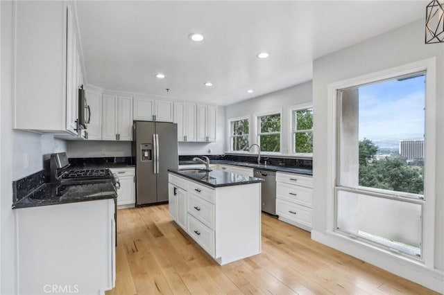 kitchen with white cabinetry, an island with sink, appliances with stainless steel finishes, light hardwood / wood-style flooring, and sink