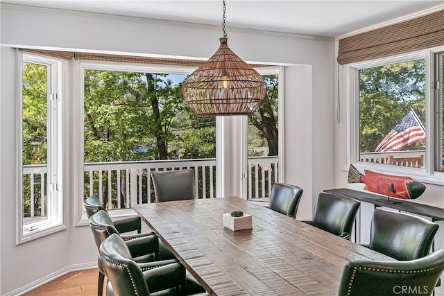 dining area featuring wood-type flooring, a wealth of natural light, and ornamental molding