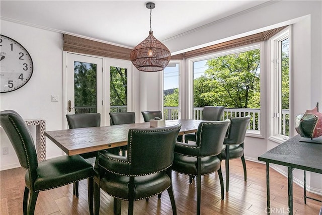 dining room with light wood-type flooring, a wealth of natural light, and ornamental molding