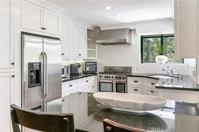 kitchen featuring white cabinets, sink, wall chimney exhaust hood, decorative backsplash, and appliances with stainless steel finishes